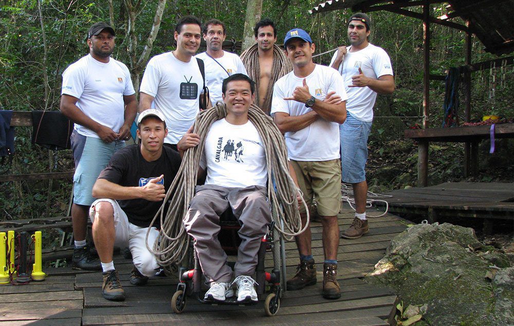 Ricardo Shimosakai de cadeira de rodas e corda no pescoço após descer de rapel o Abismo de Anhumas em Bonito/MS