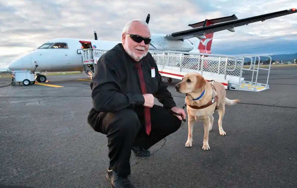 James Bennett e seu cão-guia, Brogan, preparam-se para embarcar em um avião da QantasLink para seu 200º vôo juntos