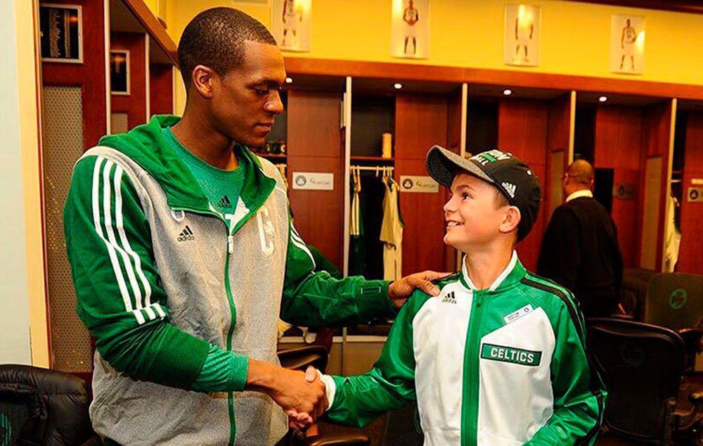 Louis Corbett cumprimenta Rajon Rondo, um dos atletas do Boston Celtics, time de basquete americano do qual é fã. Recordação para sempre.