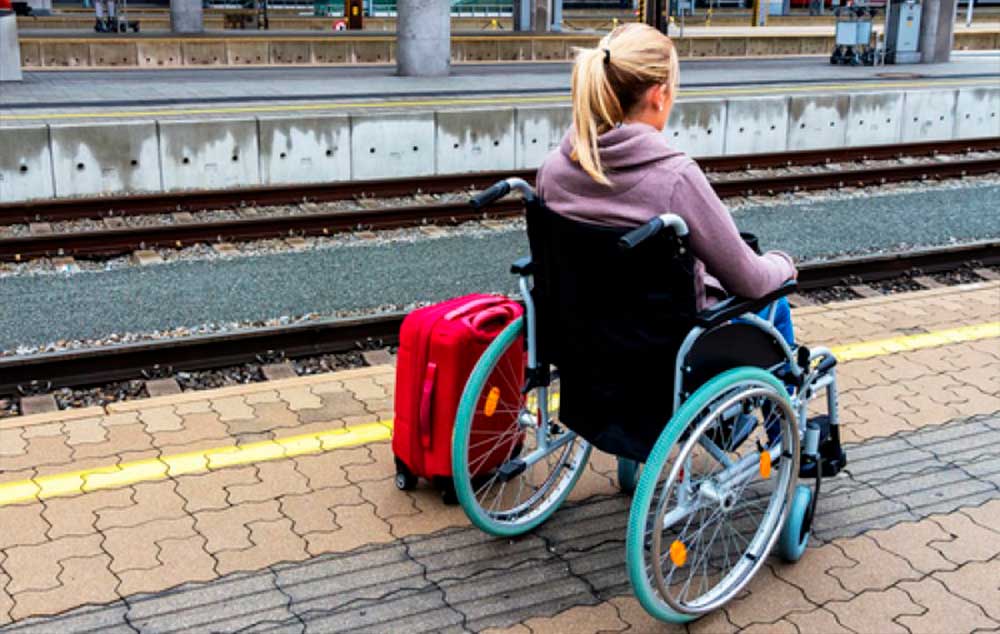 Una pasajera em silla de ruedas con su equipaje espera para subir al tren