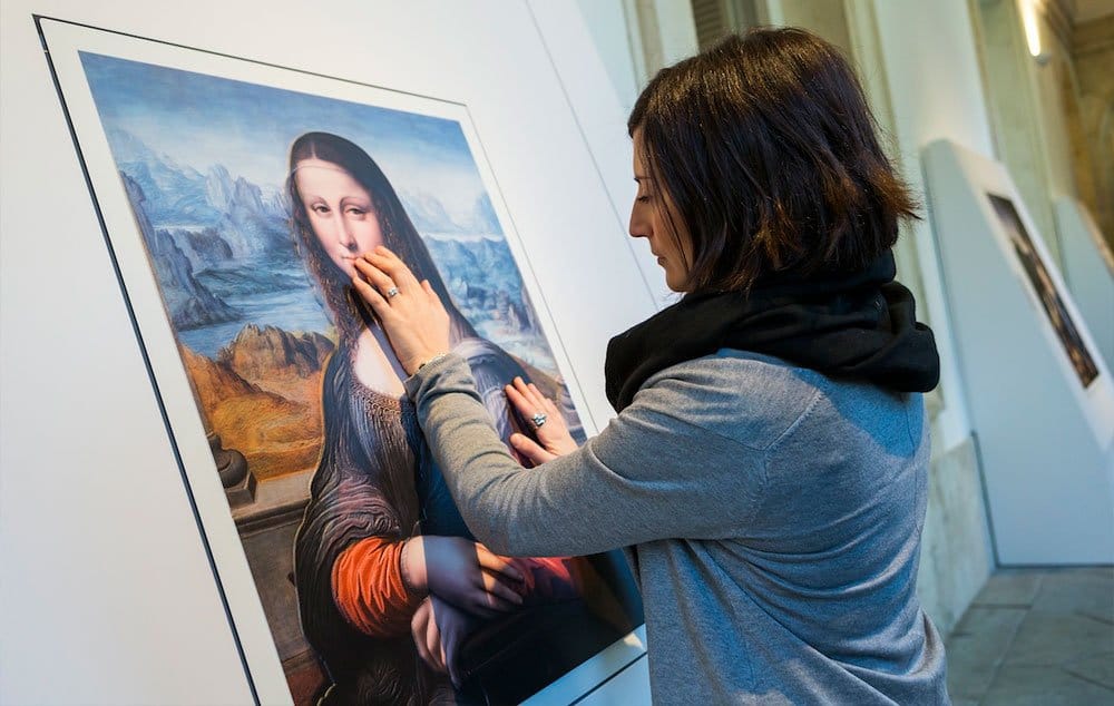 A visitor to the exhibition touches an augmented images of “La Gioconda,” believed to have been painted by an apprentice of Leonardo.