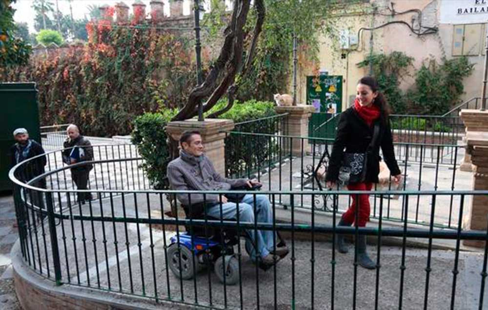 Antonio Hierro sube por una rampa con su silla de ruedas, en un recorrido por los Jardines de Murillo, en compañía de Sara López