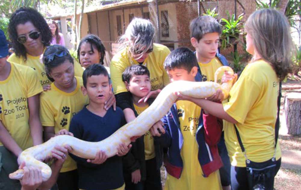 Crianças cegas tem a experiência de tocar em uma cobra no Zoológico de Brasília