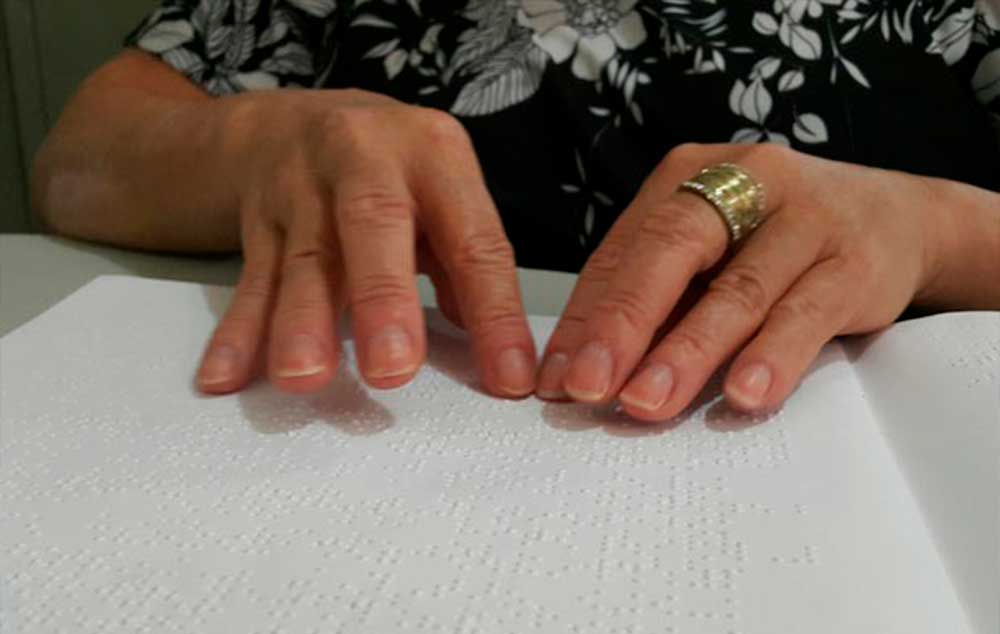 Muher com deficiência visual lê livro em Braille em biblioteca de Taguatinga, no Distrito Federal