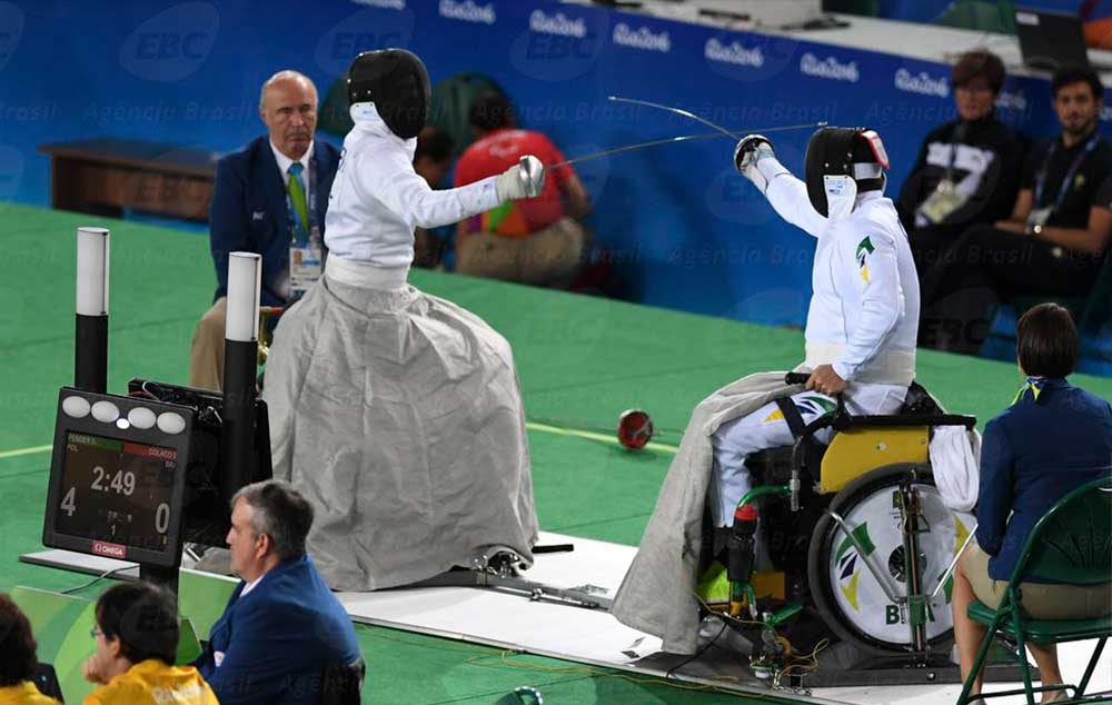 Nas disputas de espada, os atletas usam uma manta metálica para proteger suas pernas e as rodas da cadeira