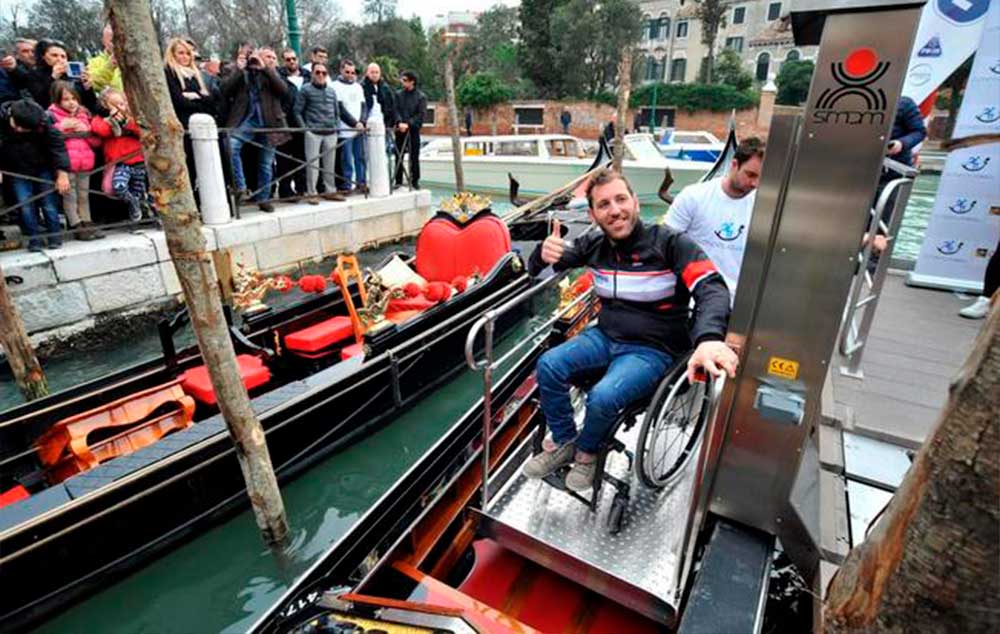 A man sitting on a wheelchair is boarded on a gondola in Venice, Italy