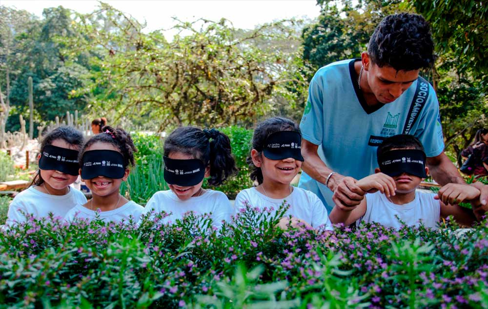 Los niños caminan por el jardín sensorial con los ojos vendados, guiado por una persona ciega, simplemente a tocar y oler las plantas.