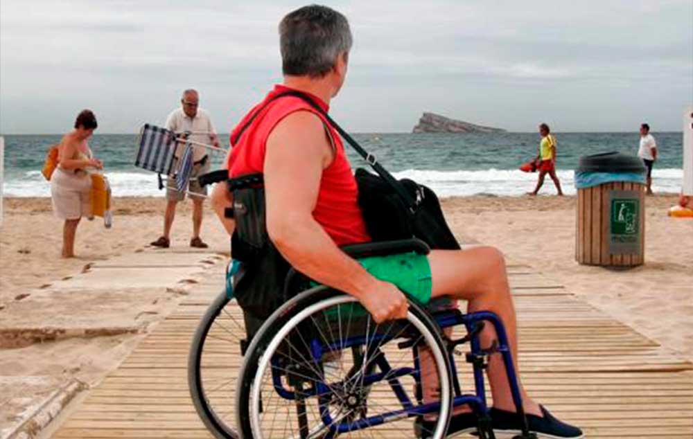 Un hombre en silla de ruedas en una de las pasarelas de las playas de Benidorm.