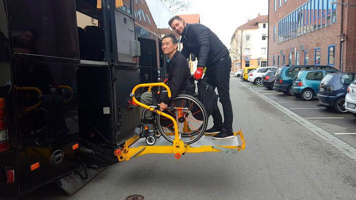 Ricardo Shimosakais is with an attendant, on top of a lift platform of a road bus