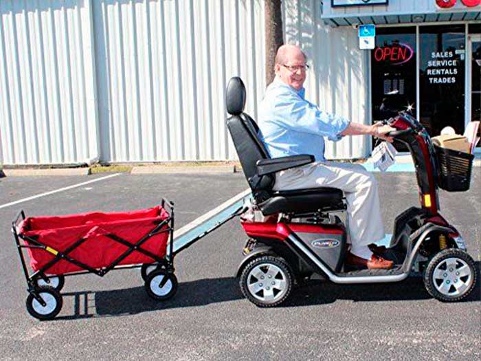 Homem sentado em uma scooter, puxando um carrinho à reboque